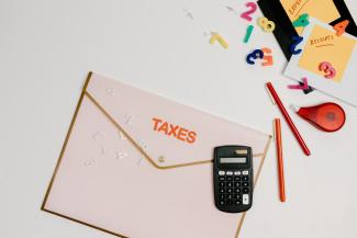 A folder with the word "TAXES" on it. There is various stationery scattered around the folder.